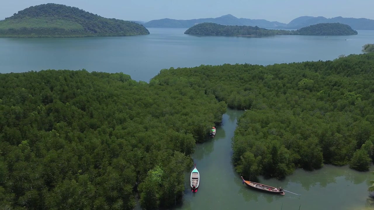 Cảnh quay drone từ trên cao rừng ngập mặn dày đặc với một kênh thủy triều hẹp và những chiếc thuyền neo đậu đổ ra biển lặng với những hòn đảo rải rác và đất liền Krabi hiện rõ trong khung cảnh nhiệt đới