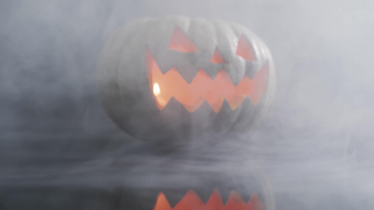 efecto de humo sobre cara aterradora tallada calabaza de halloween contra un fondo gris