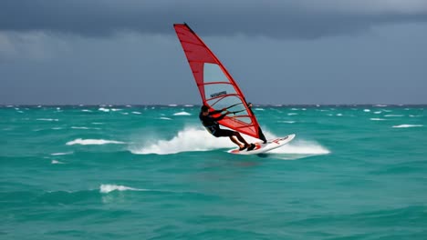 windsurfers navigate turquoise waters under an overcast sky