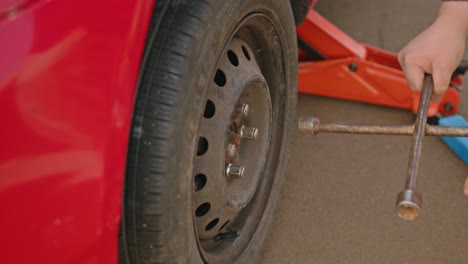 man screws a spare wheel onto a lifted vehicle