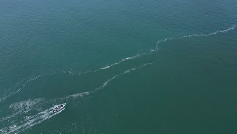 Aerial-of-small-boat-slowly-gilding-over-sea-water-surface-during-sunshine-day