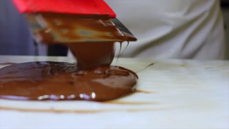 tempering melted chocolate on natural stone with spatula close-up