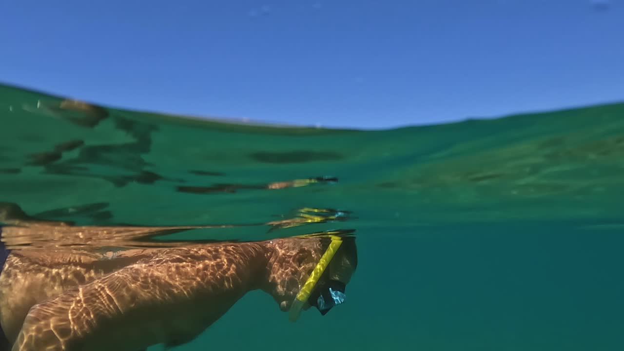 이탈리아 아브루초의 트라보치 낚시 플랫폼을 따라 푸른 아드리아 해에서 수영하는 마스크와 노란색 스노클을 착용한 성인 남성의 수중 풍경 반쪽