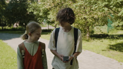 two young students walking and talking outdoors on a sunny day