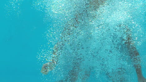 brunette woman floating underwater in blue swimsuit