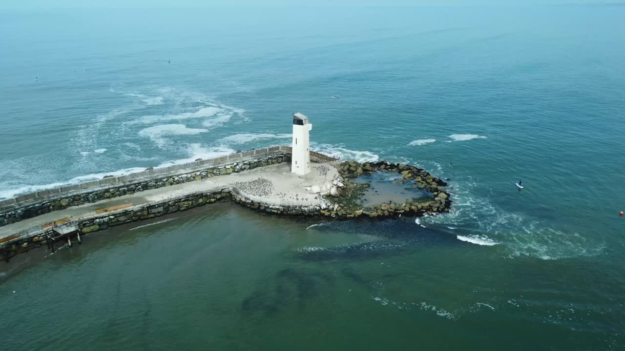 pequeño faro blanco al final de un muelle rocoso