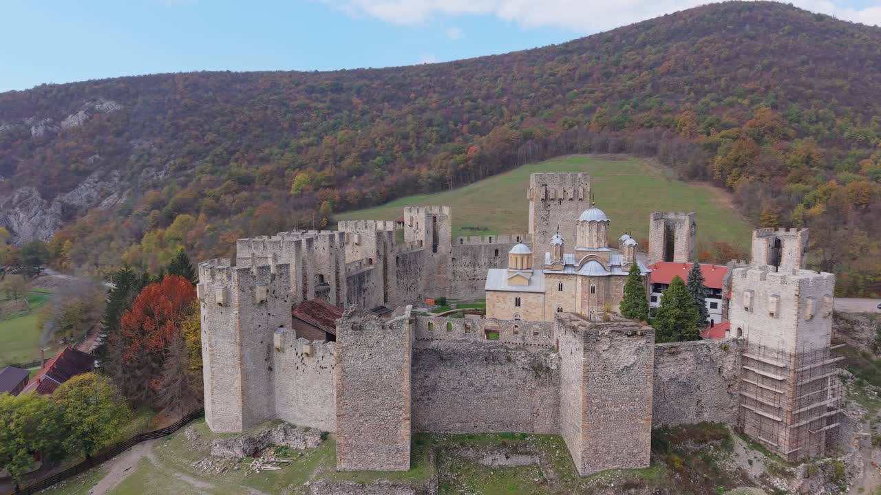 Orbitální záběr kláštera Manasija z dronu, zachycující jeho středověkou architekturu, hradby a malebnou okolní krajinu ze všech úhlů.