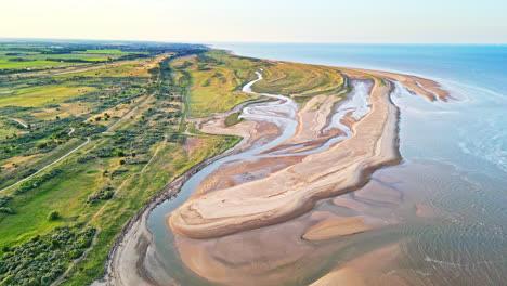 Entdecken-Sie-Den-Idyllischen-Charme-Einer-Küstenszene-Zur-Goldenen-Stunde-Durch-Atemberaubende-Drohnenaufnahmen-Aus-Der-Luft:-Flussmündung,-Sandbänke,-Meer-Und-Marschland