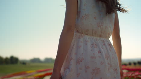 Unrecognizable-woman-with-camera-looking-back-at-garden-with-spring-flowers.