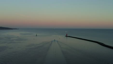 drone-view-of-boat-cruising-at-the-great-south-wall,-Dublin-during-sunset