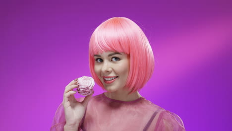 close up of cute woman eating little cake with pink cream and smiling 1