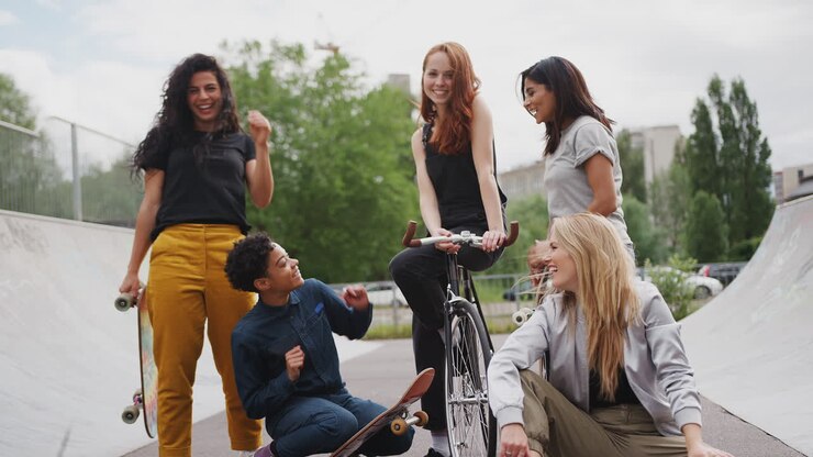 Ritratto di amiche con skateboard e bicicletta in piedi in uno skate park urbano