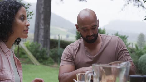 happy biracial couple enjoying meal at dinner table in garden, slow motion