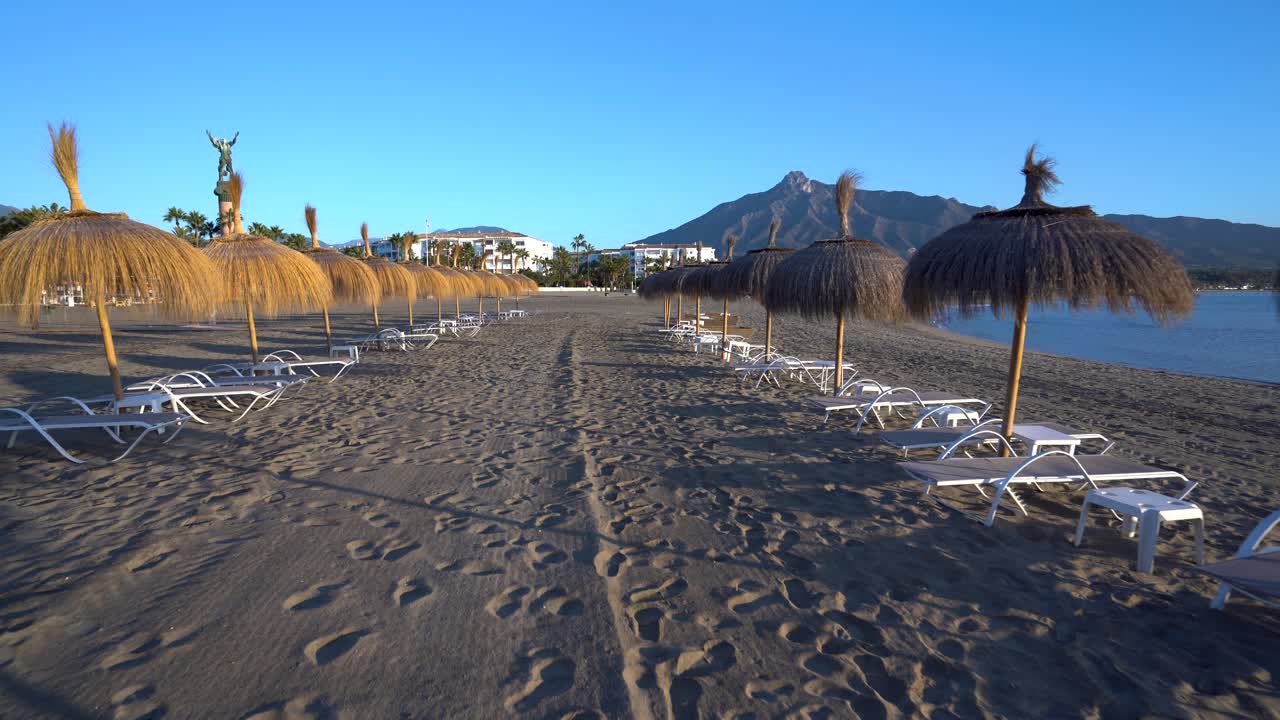 Spiaggia di Puerto Banus, ripresa stabilizzata con gimbal che scivola tra ombrelloni e lettini, perfetto filmato di viaggio di lusso di Marbella, Costa del Sol.