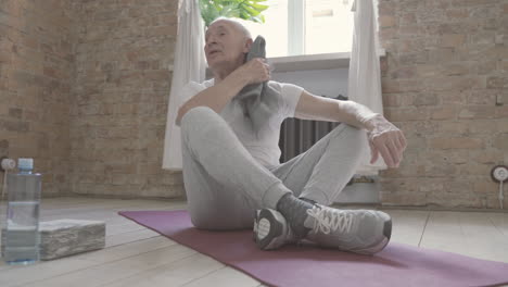 Viejo-Macho-Descansando-Y-Sentado-En-Una-Alfombra-De-Yoga-En-Casa