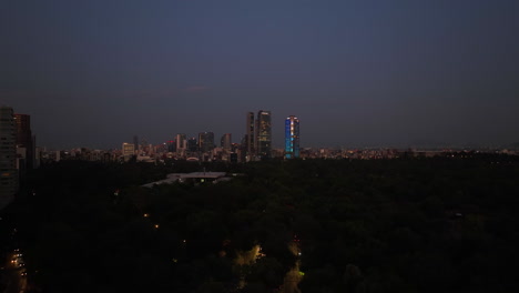 Vista-Aérea-Sobre-El-Parque-De-Chapultepec-Con-Los-Rascacielos-Del-Centro-Al-Fondo,-Atardecer-En-La-Ciudad-De-México