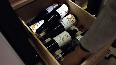 slow motion shot of person selecting wine bottle from drawer