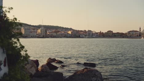 A rocky coastline at Mitylene port with waves gently hitting the shore, overlooking the Aegean Sea under a clear sky.