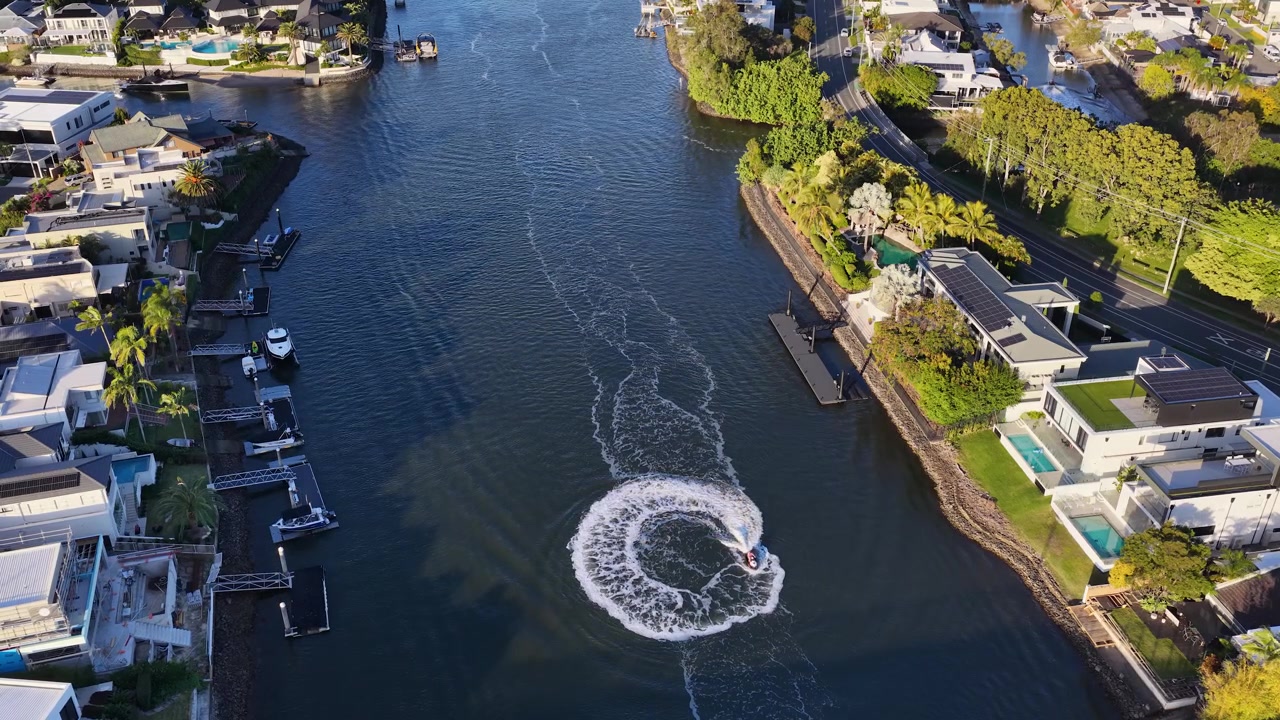 Ripresa aerea con drone di moto d'acqua che girano in cerchio in un canale fiancheggiato da ville di lusso