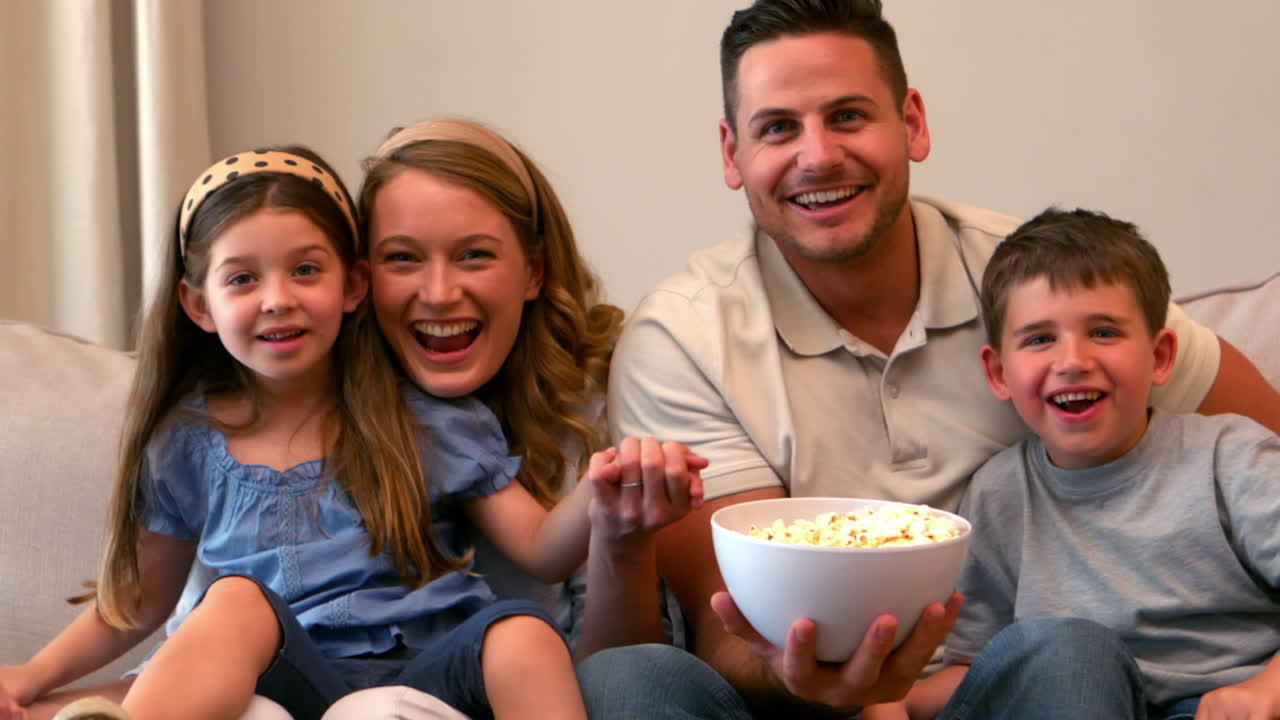 familia feliz viendo la televisión comiendo palomitas de maíz