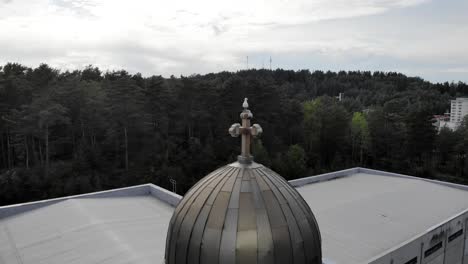 drone shot around a bird on a church cupole cross, dark, overcast day, in gotland, sweden - circling, aerial view