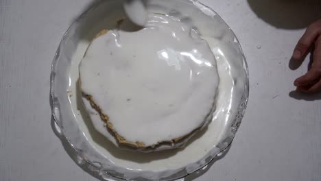 hombre regando pastel de esponja con crema blanca y lo mancha en la superficie. preparación de postre dulce. la vista desde la parte superior. 4k.