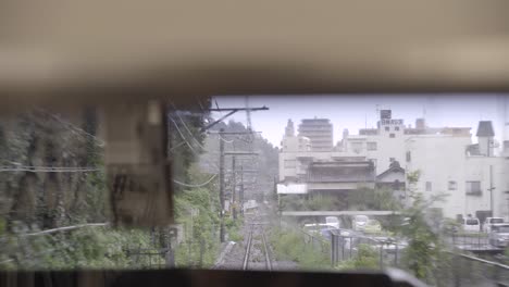 view out of back of train window on tracks, shaking as train is driving fast in city