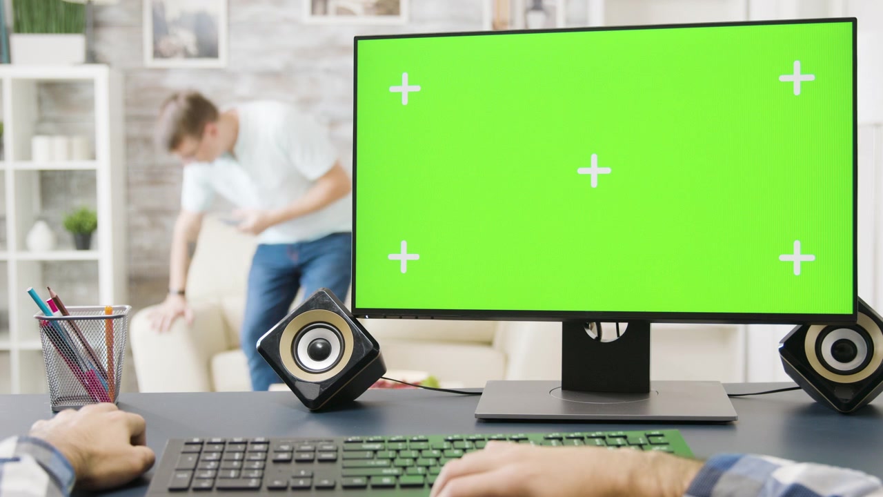 Person Working on Computer with Green Screen Monitor in Home Office