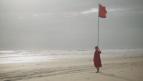 Ein-Wunderschönes-Junges-Indisches-Mädchen-Mit-Einem-Wunderschönen-Roten-Kleid,-Das-An-Einem-Sonnigen-Tag-Am-Strand-Steht-Und-Einen-Urlaub-Genießt