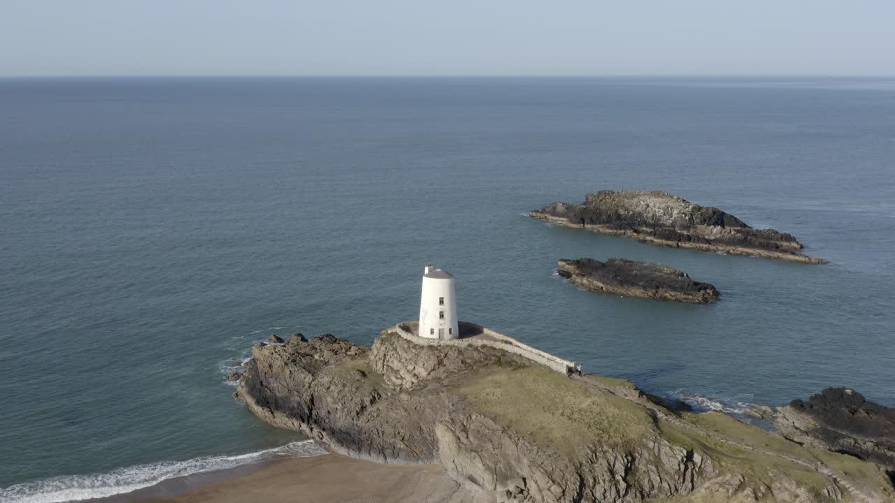 una vista aérea del faro twr mawr en la isla ynys llanddwyn, volando de izquierda a derecha alrededor del faro, anglesey, norte de gales, reino unido