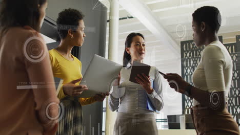 Animation-of-graphs,-numbers,-loading-circles,-bars,-diverse-female-coworkers-discussing-in-office