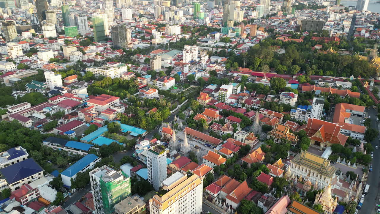 Wide aerial video of central Phnom Penh, showing a dense patchwork of red and blue rooftops mixed with modern construction and temple complexes