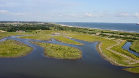 aerial wide orbit shot over the green meadows of waterdunes - a nature area and recreational park in the province of zeeland, the netherlands