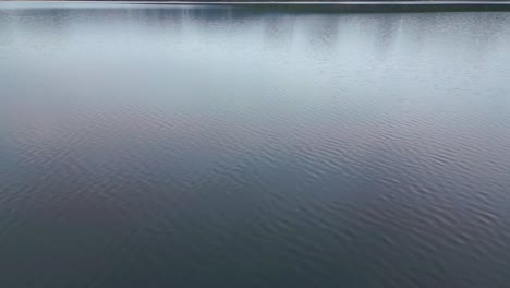 travelling across a lake then tilting up to reveal picturesque white mountains