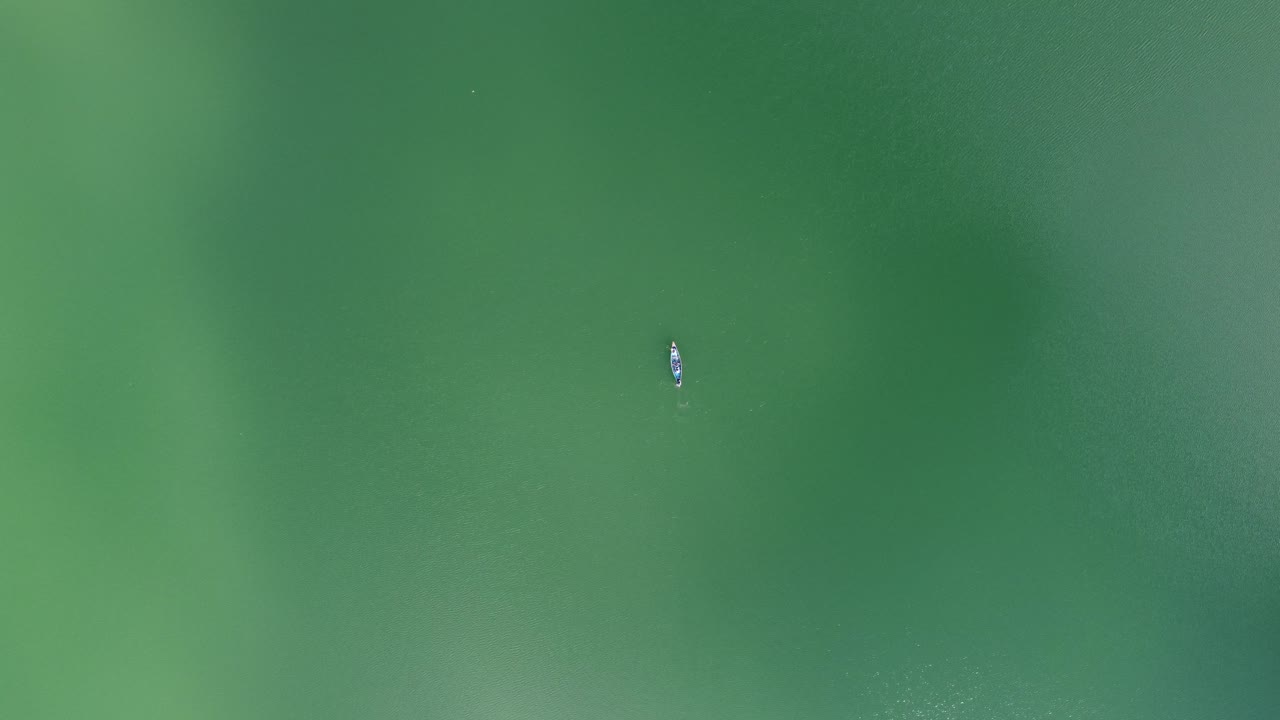 vista aérea de personas remando un bote de madera en un lago o mar azul turquesa