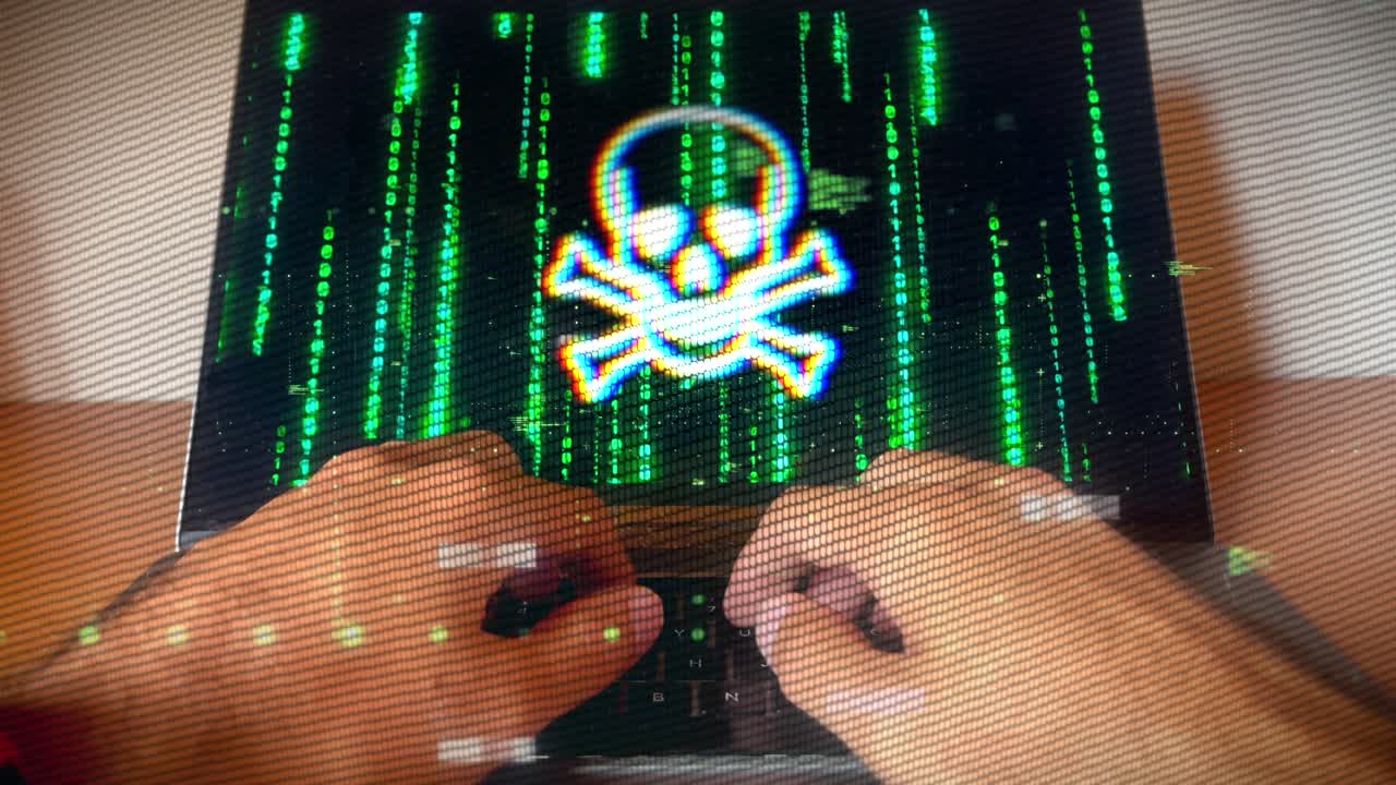 Hacker typing as malware warning symbol displays on screen