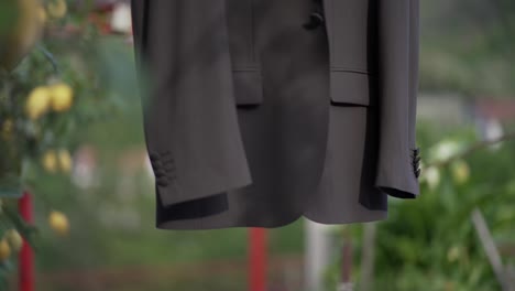 Hanging-suit-jacket-outdoors-with-a-blurred-green-background