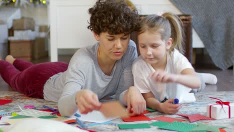 Glückliche-Mutter-Spielt-Mit-Ihrer-Tochter,-Die-Zu-Weihnachten-Auf-Dem-Boden-Liegt