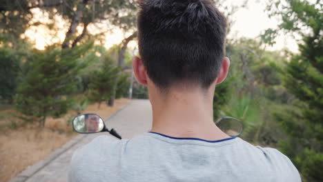 rear view of a teenager riding a scooter cheerful and active recreation