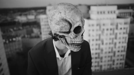 man in a skull mask on a rooftop in black and white
