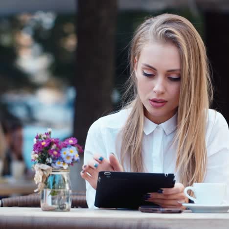 Beautiful-young-woman-uses-a-tablet-in-a-cafe