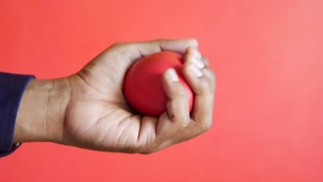 person squeezing a red stress ball