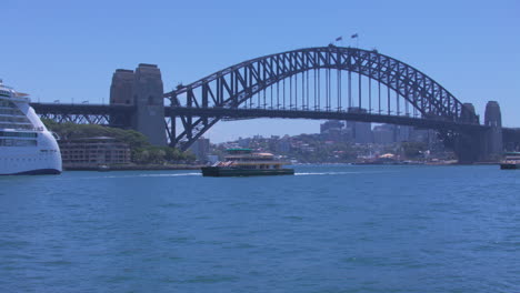a sydney ferry pulls into dock at circular quay on a bright sunny day with the harbor bridge in the background in sydney australia