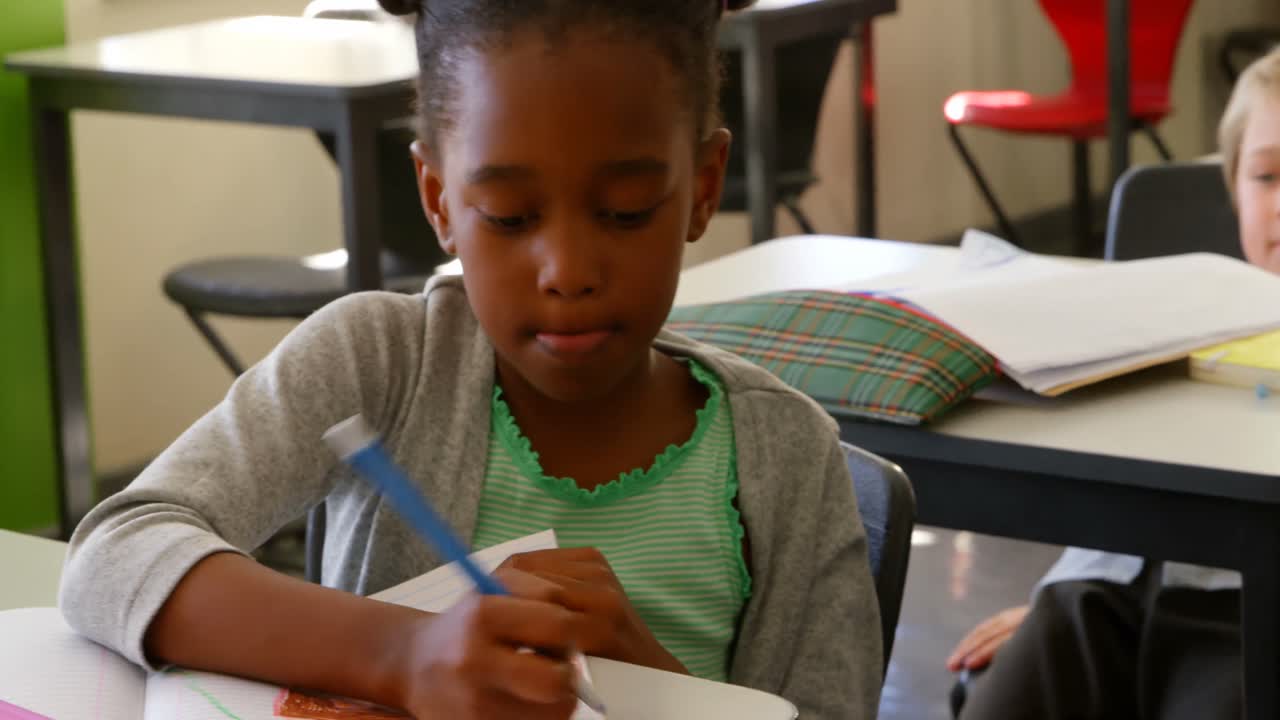 African American schoolgirl studying at desk in classroom at school 4k