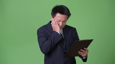 mature japanese businessman against green background