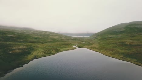 Forward-drone-shot-over-a-lake-in-Nordkapp-on-a-cloudy-summer-day