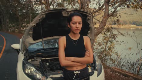 woman with a broken down car by a lake