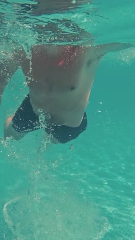 young guy swims underwater in a swimming pool