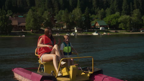 mom and daughter ride catamaran swinging on waves. woman points finger and surprised girl exclaims with amusement slow motion. active recreation in nature