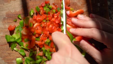 cook slicing red and green bell peppers in small cubes